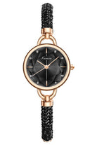 Watch with black dial and beaded strap with rose gold case on white background.