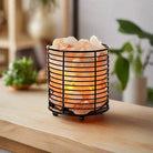 Cylindrical Himalayan salt lamp with iron frame emitting warm light for relaxation and air purification