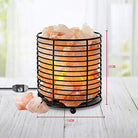 Cylindrical Himalayan salt lamp with iron frame emitting warm light for relaxation and air purification