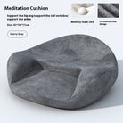 Round ergonomic meditation cushion placed on a yoga mat, with a serene background of plants and candles