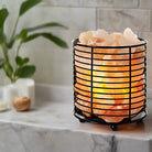 Cylindrical Himalayan salt lamp with iron frame emitting warm light for relaxation and air purification